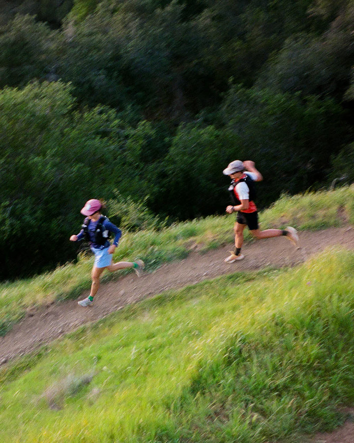 Two runners on a trail with greenery in the background