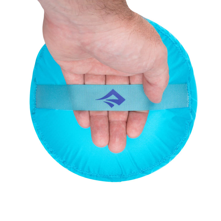 Hand holding a blue wristband with a logo on a white background