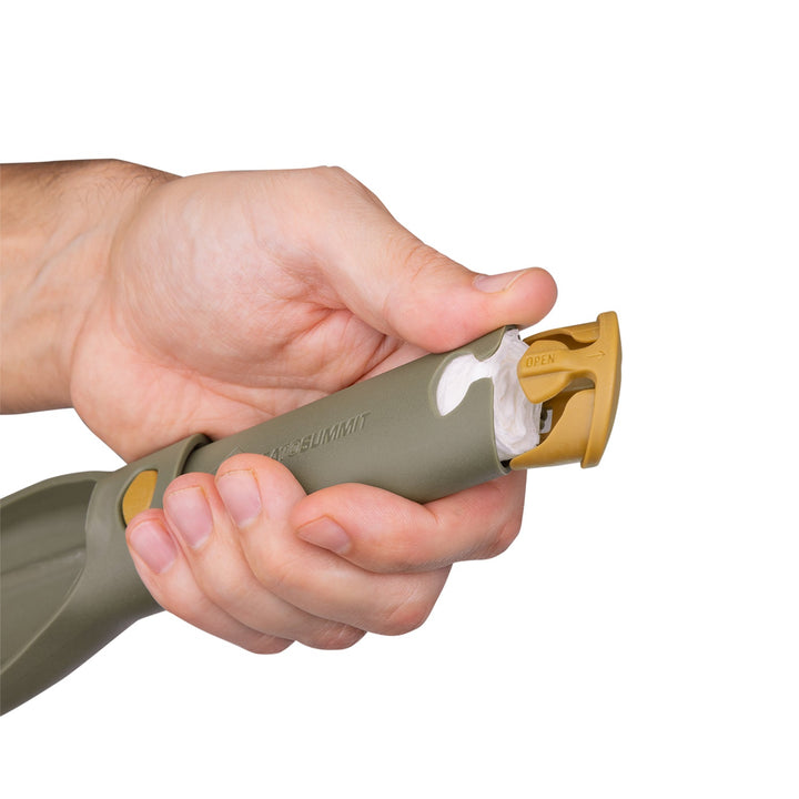 Hand holding a collapsible plastic trowel, showing toilet paper stored inside the handle