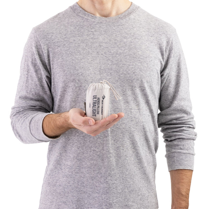 Person holding a slightly larger white stuff sack in one cupped hand