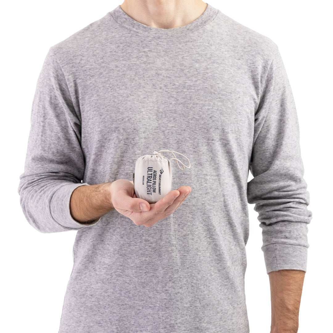 Person holding a small white stuff sack in one cupped hand