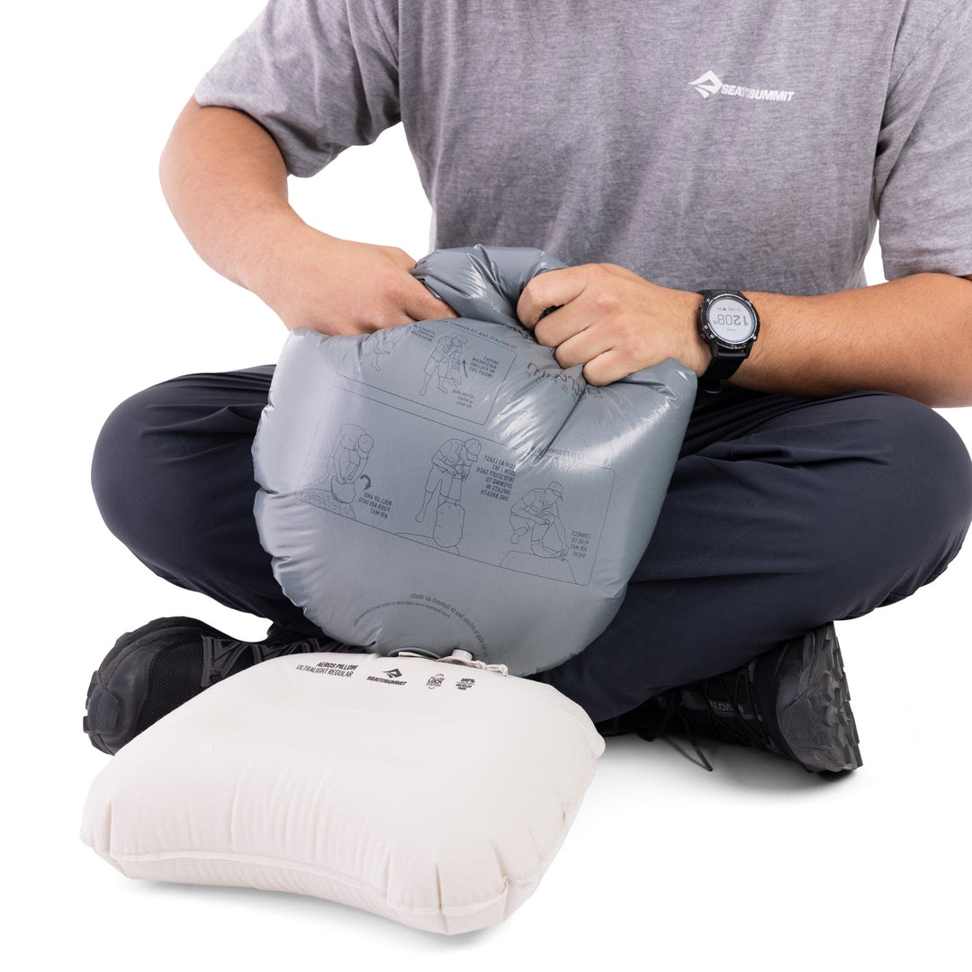 Person inflating a pale pink pillow with a gray pump sack