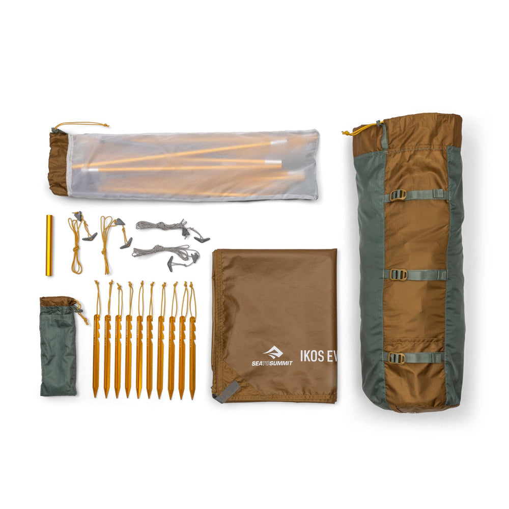 Brown and green tent in its bag along with accessories arranged on a white background. 