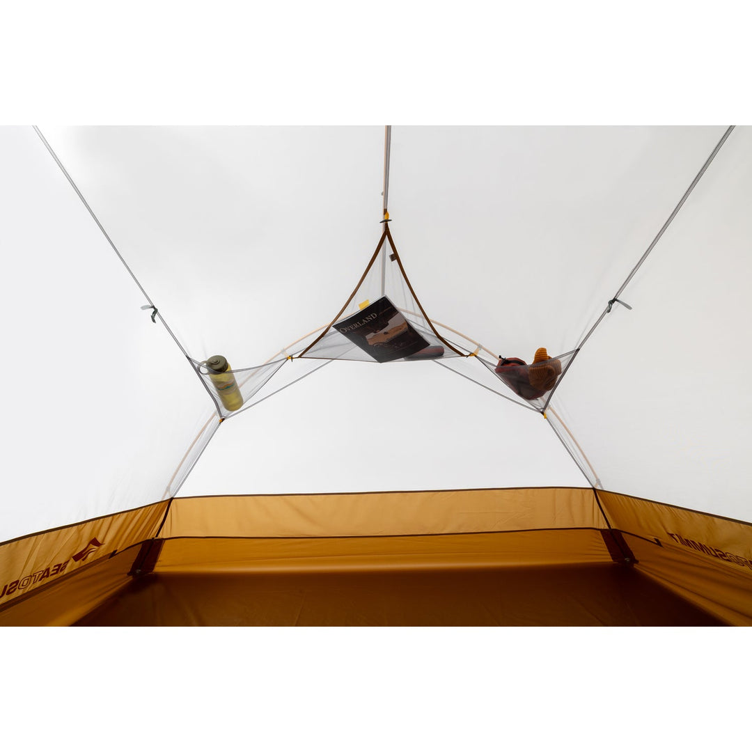 Inside of a white tent with brown floor and mesh pocket.