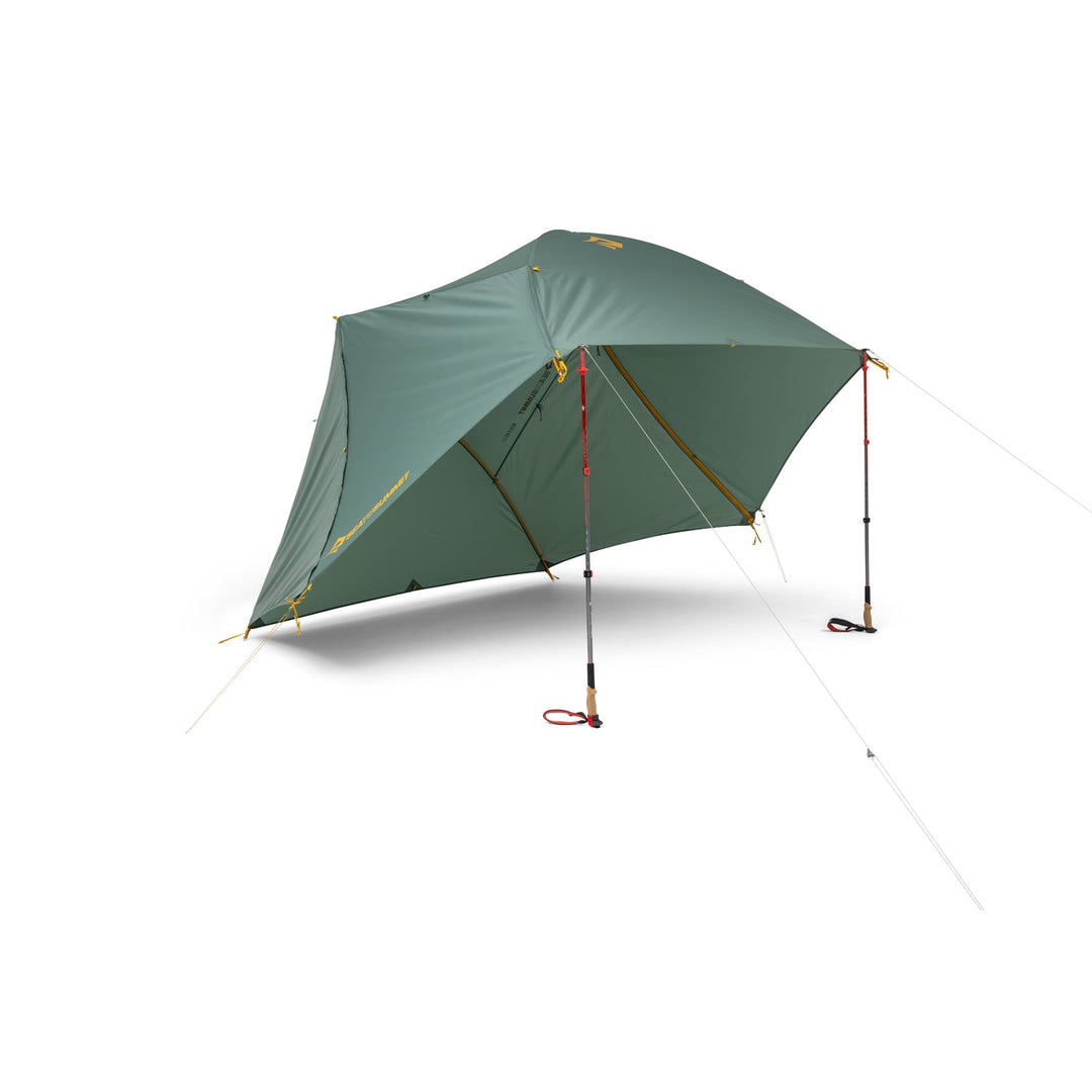 Green tent fly elevated by two hiking poles on a white background.