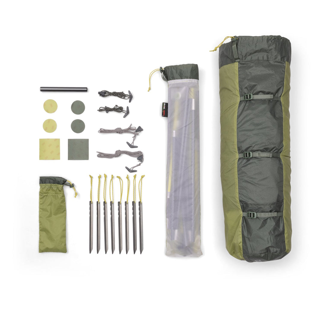 Grey and Green tent in its bag with poles, pegs, and other accessories arranged on white background.