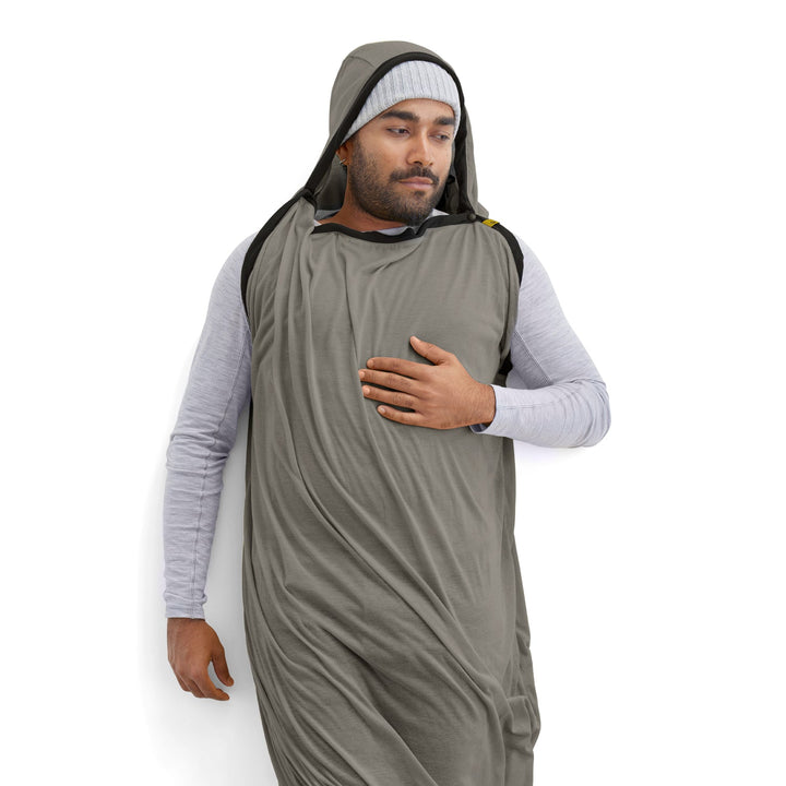 Man wearing a grey hooded sleeping bag liner on a white background