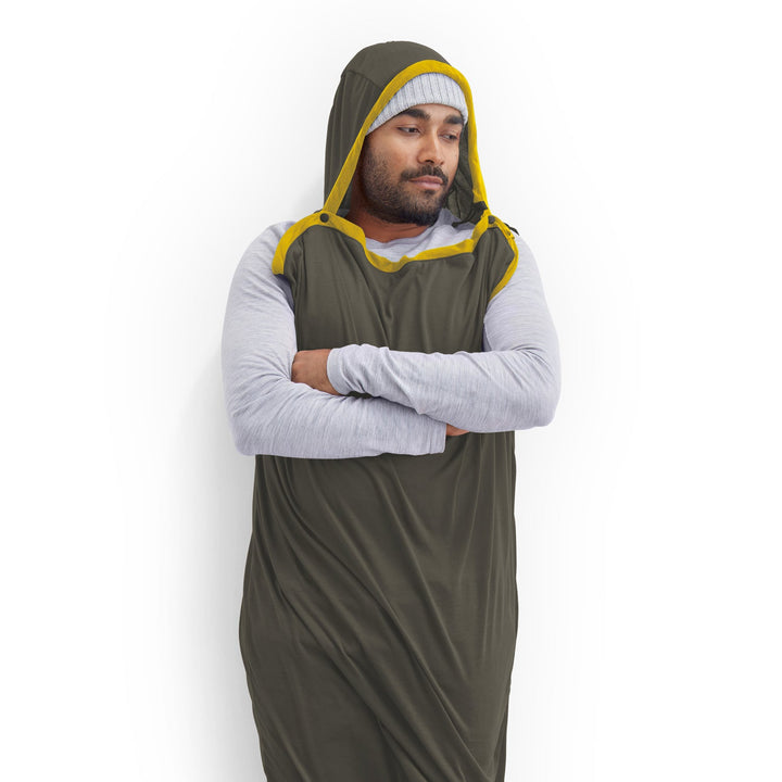 Person wearing a dark grey and yellow hooded sleeping bag liner on a white background