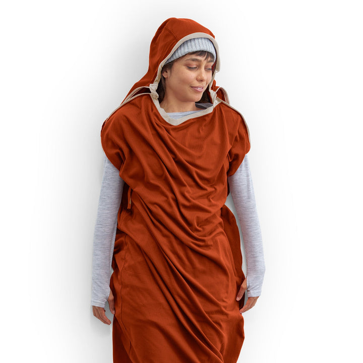 Person wearing a red hooded sleeping bag liner on a white background