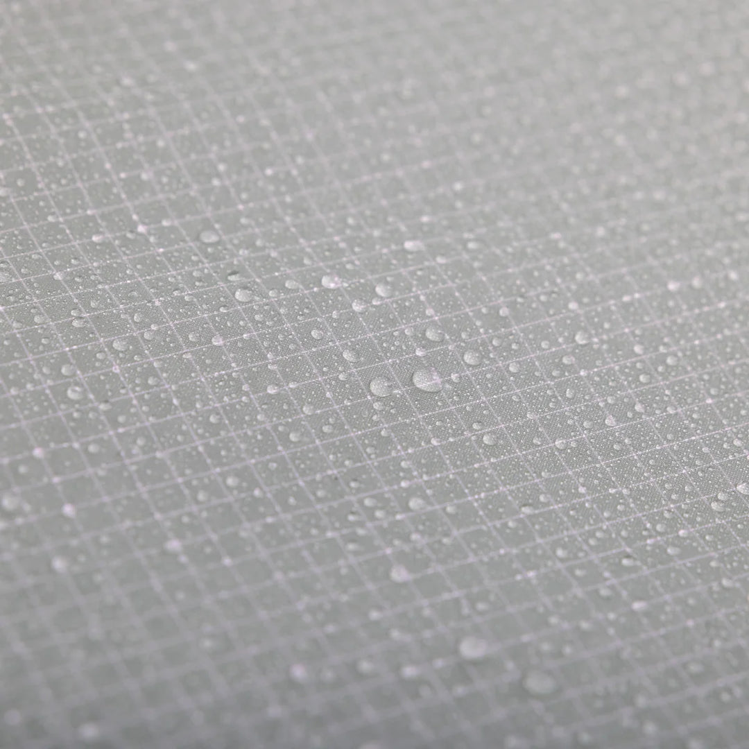 Close-up of a light gray textured surface with a subtle grid pattern and scattered water droplets.
