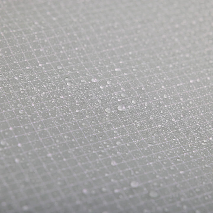 Close-up of a light gray textured surface with a subtle grid pattern and scattered water droplets.