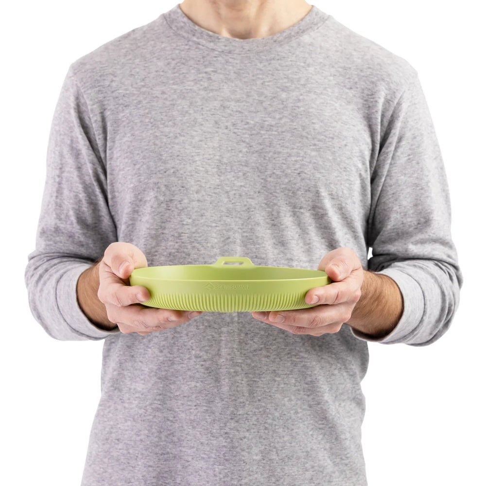 Person holding a green plastic plate against a white background.