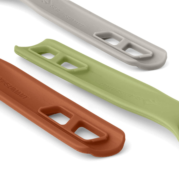 Close up of the handles of three pieces of camp cutlery, one brown, one green, and one grey