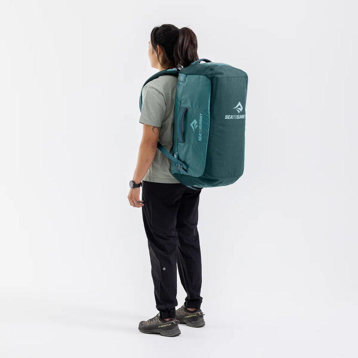 Person wearing a green backpack with a visible brand logo on a white background