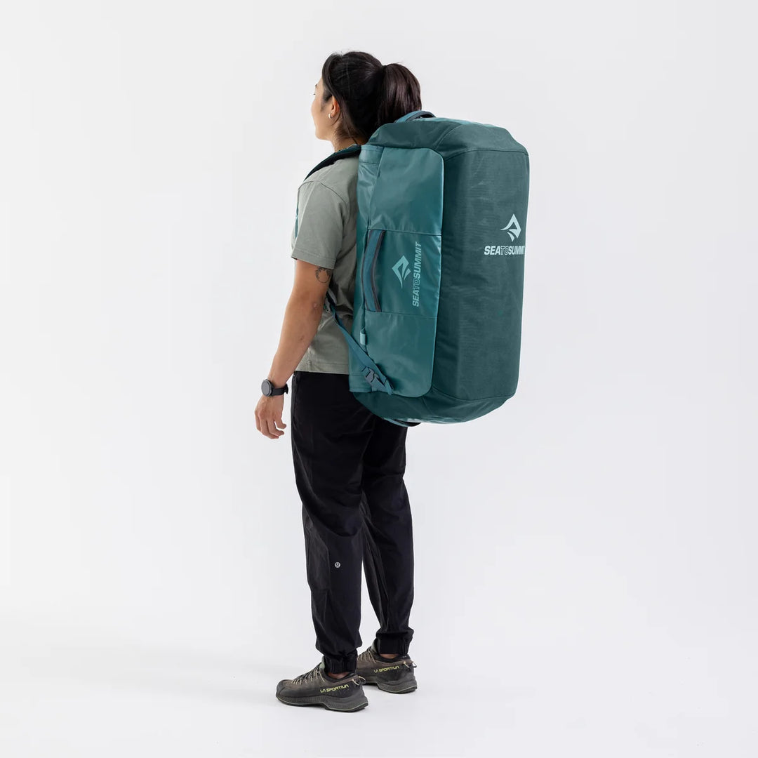 Person wearing a green backpack with a visible brand logo on a white background