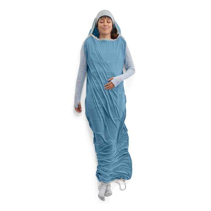 Person wearing a blue hooded sleeping bag liner on a white background