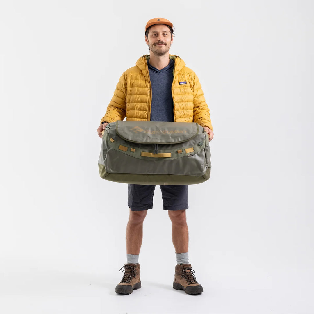 Man holding a large green bag against a white background