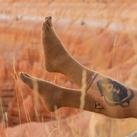 Orange wearing toe socks with a tattoo on a blurred natural background