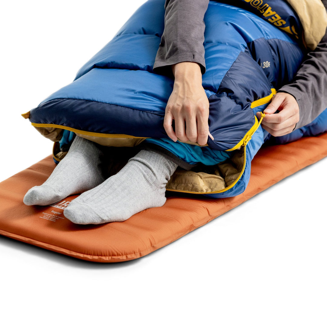 Person in a blue sleeping bag with both feet sticking out through a zip.