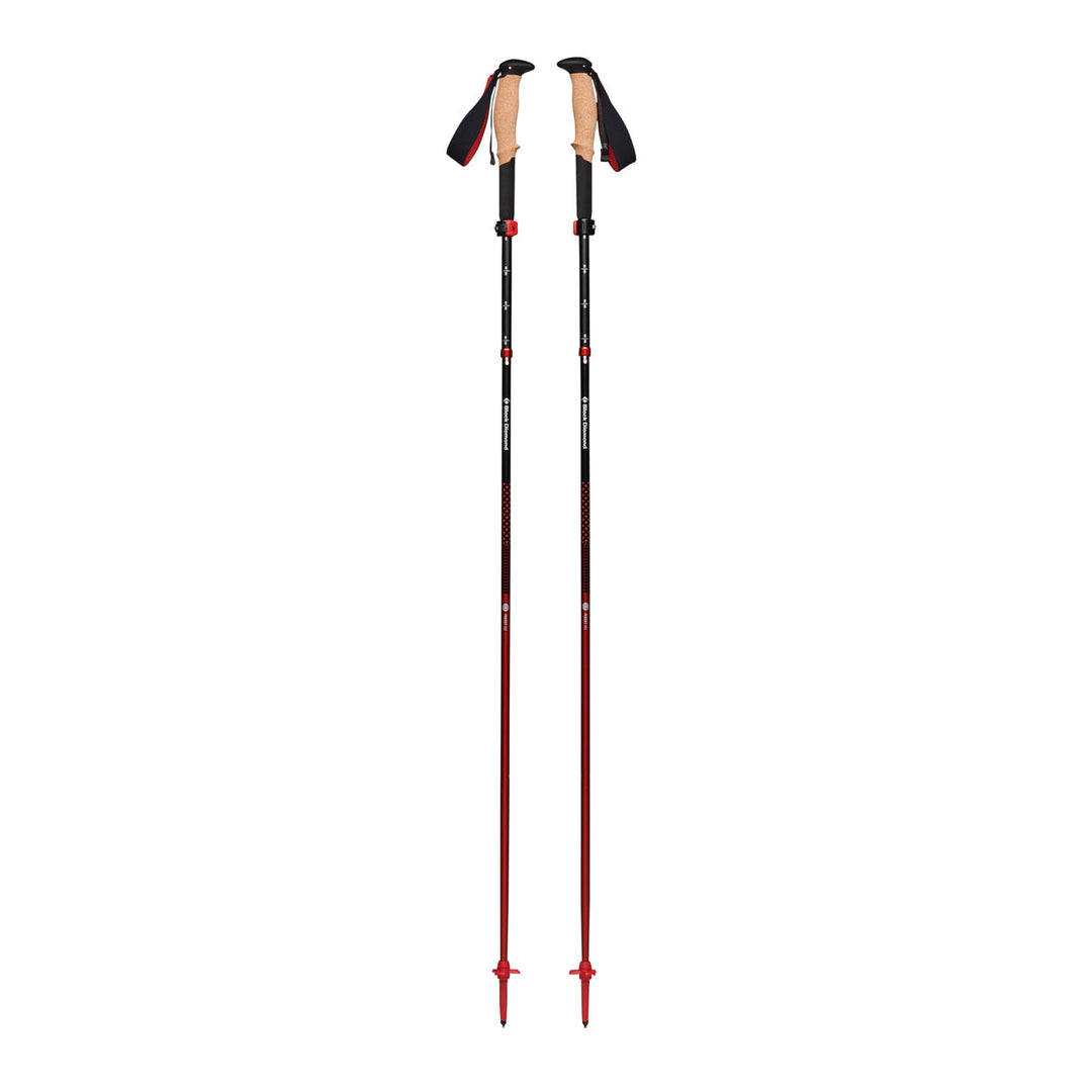 Black trekking poles with red detailing, extended, on a white background