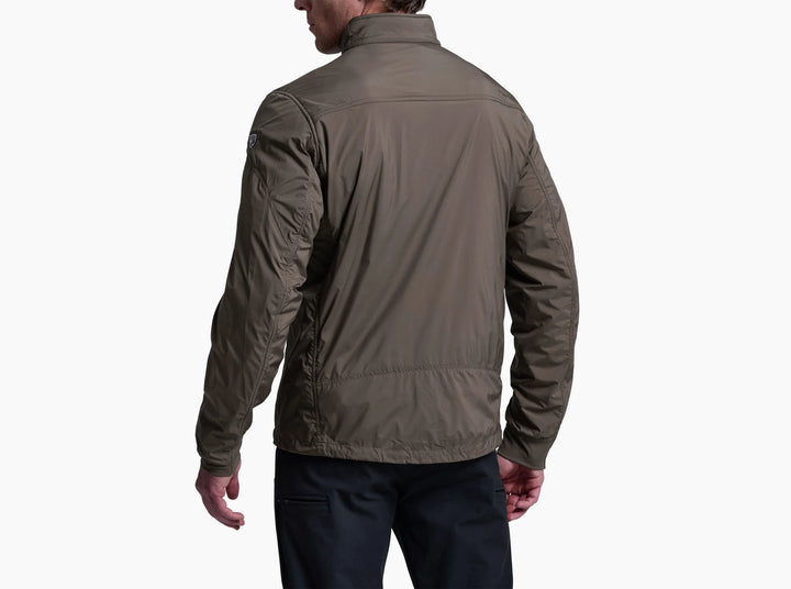 Man wearing a brown jacket and jeans viewed from behind on a dark background