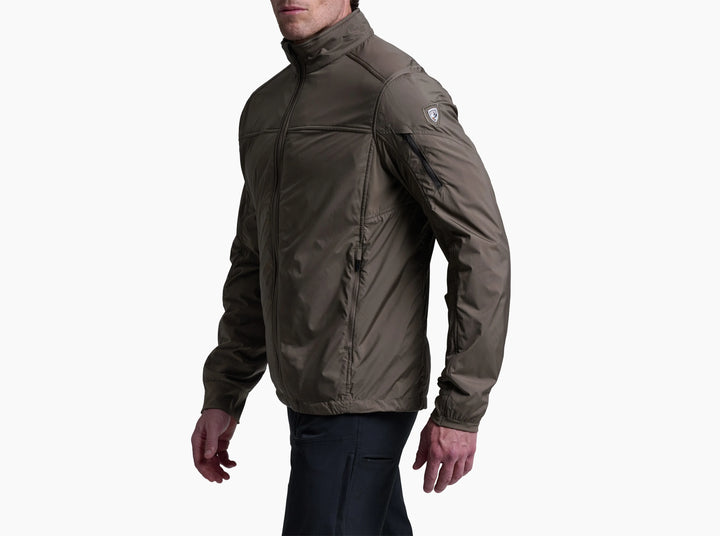 Man wearing a brown jacket and dark pants viewed side on against a white background