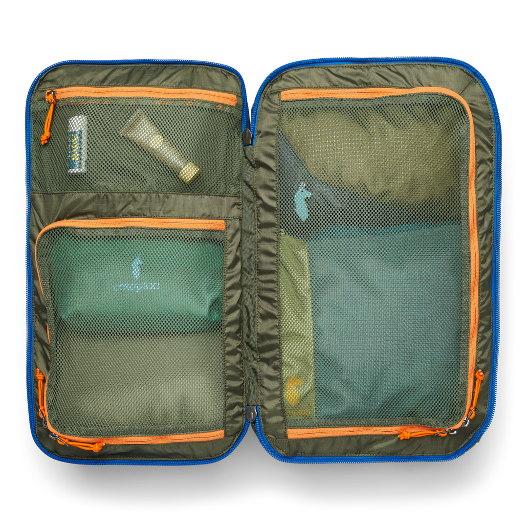 Green travel pack opened up, showing sunscreen and packing cubes in three mesh pockets