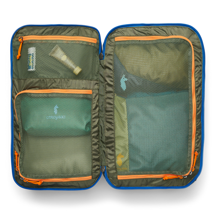 Green travel pack opened up, showing sunscreen and packing cubes in three mesh pockets