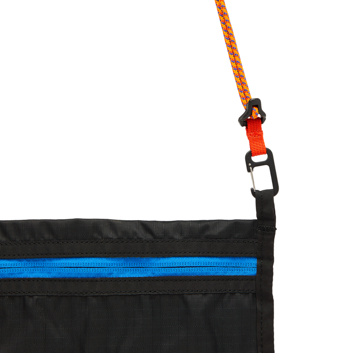 Close-up of a black cross body bag with blue zipper and orange carry cord