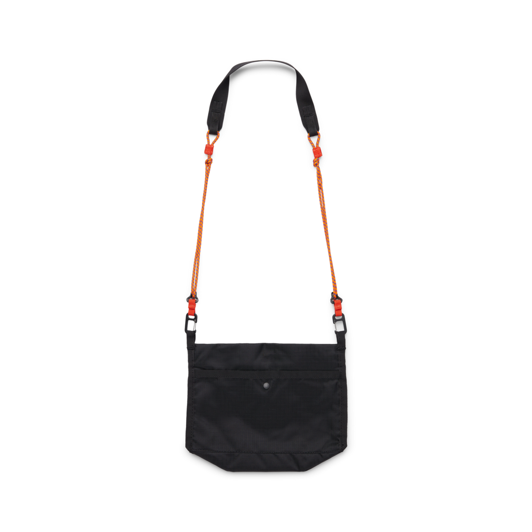 Black cross body bag with a strap made from orange cord viewed from behind on a white background