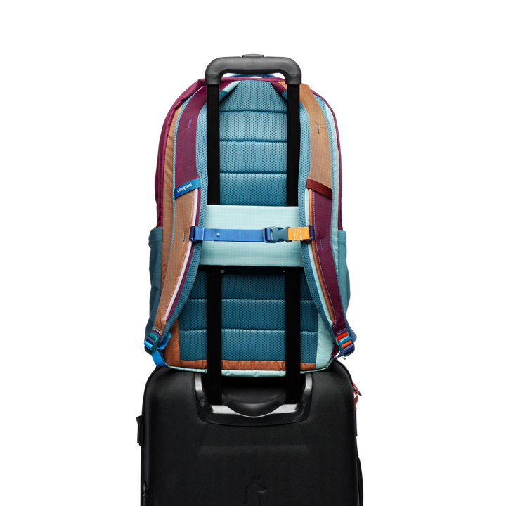 Multicolored backpack attached to a suitcase on a white background