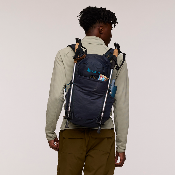 Person wearing a navy backpack with visible branding on a plain background