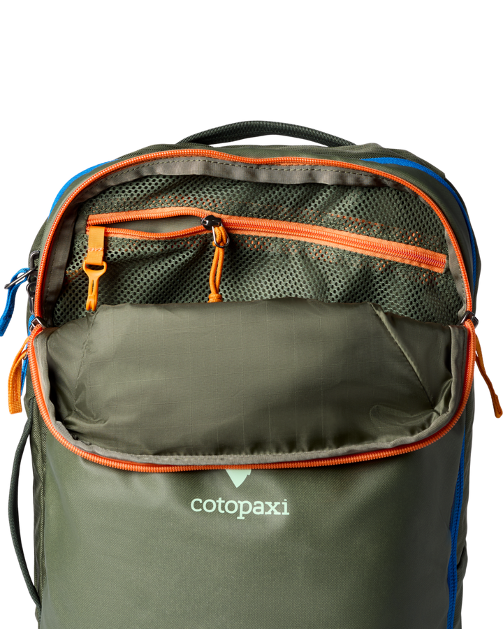Green backpack with orange and blue highlights, unzipped, with mesh pocket and key hook