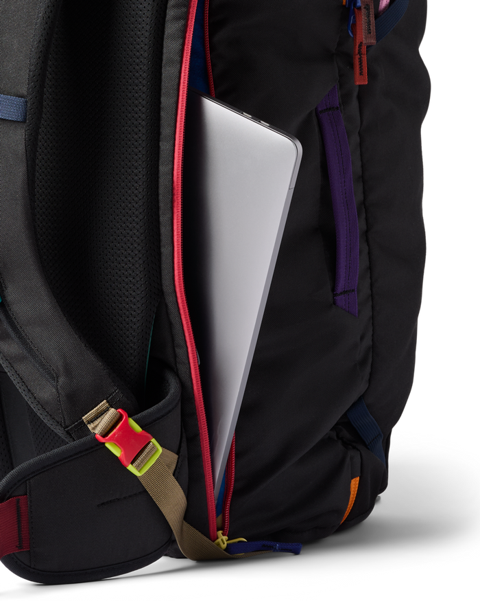 Black backpack with colorful straps holding a silver laptop on a white background