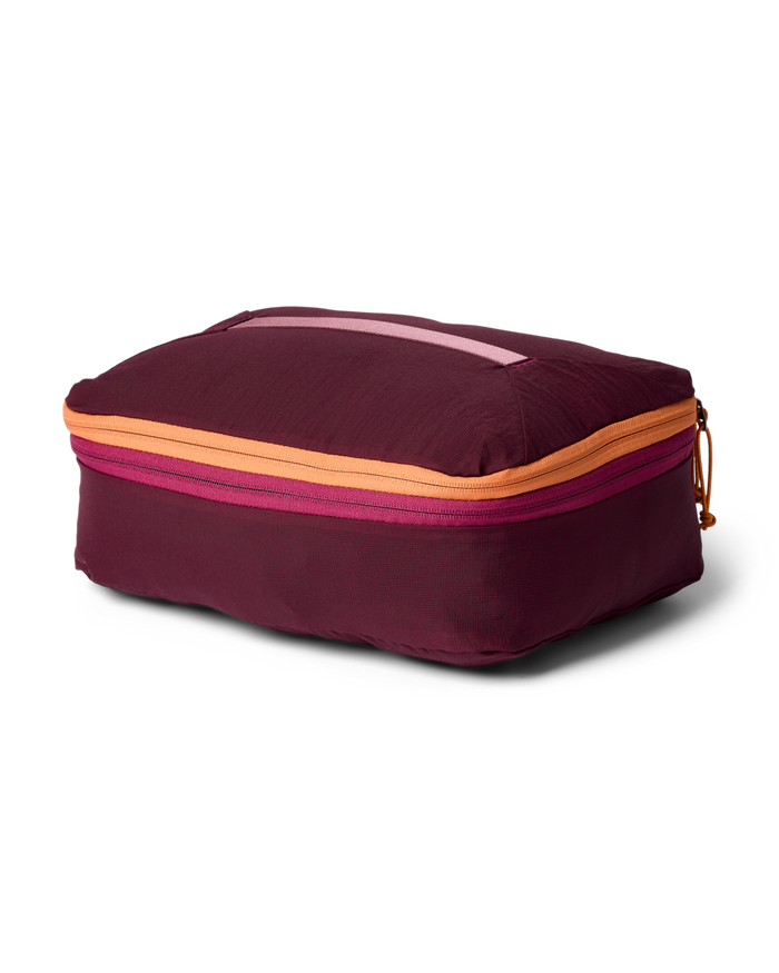 Maroon packing cube with orange zipper on a white background