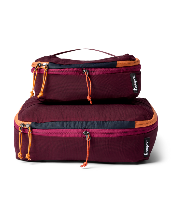 Two maroon packing cubes with orange zippers on a white background