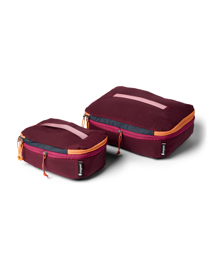 Two maroon travel packing cubes with orange zippers on a white background