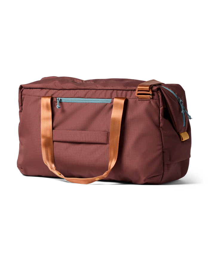 Brown duffel bag with orange handles on a white background