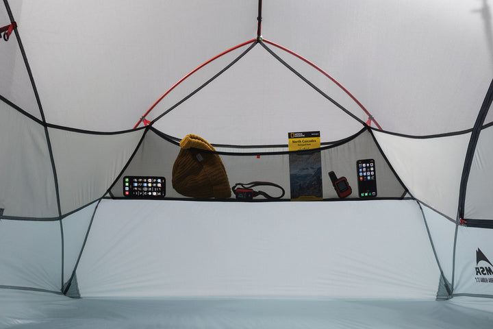 Grey tent interior with various items including a bag and electronic devices.
