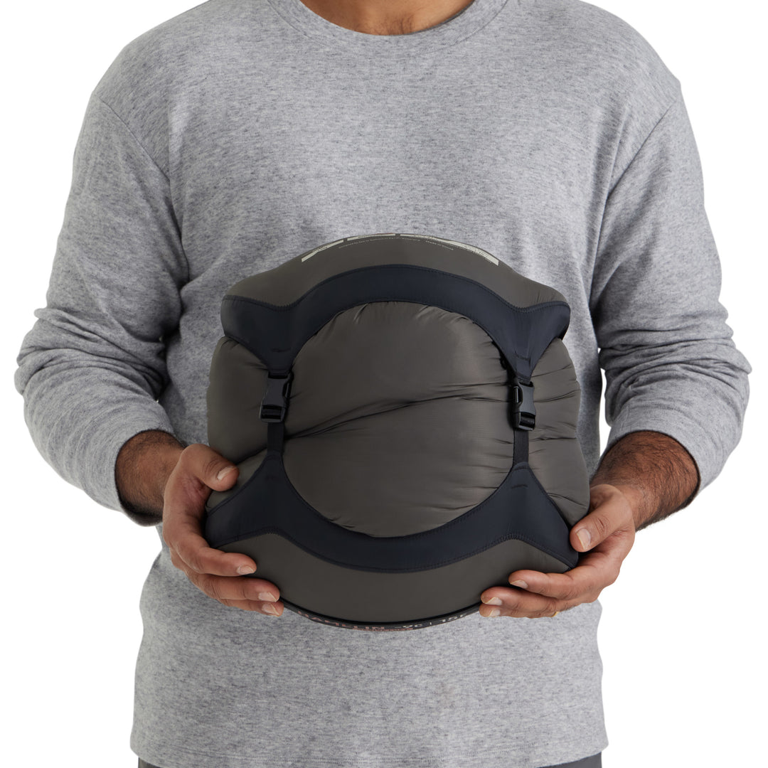 Person holding a sleeping bag in a compression sack