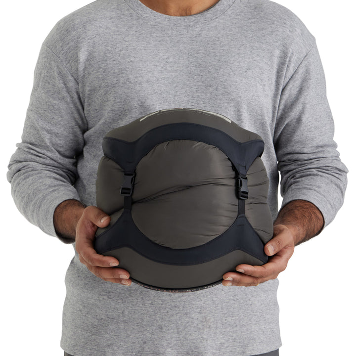 Person holding a sleeping bag in a compression sack