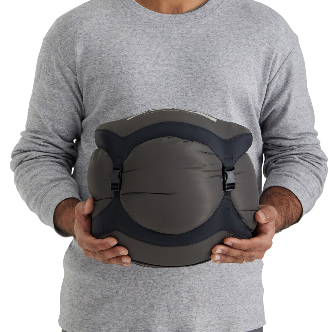 Person holding a sleeping bag in a grey compression sack