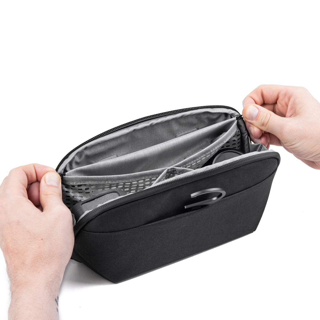 A black zippered organizer pouch with gray interior lining, shown being opened by two hands against a white background.