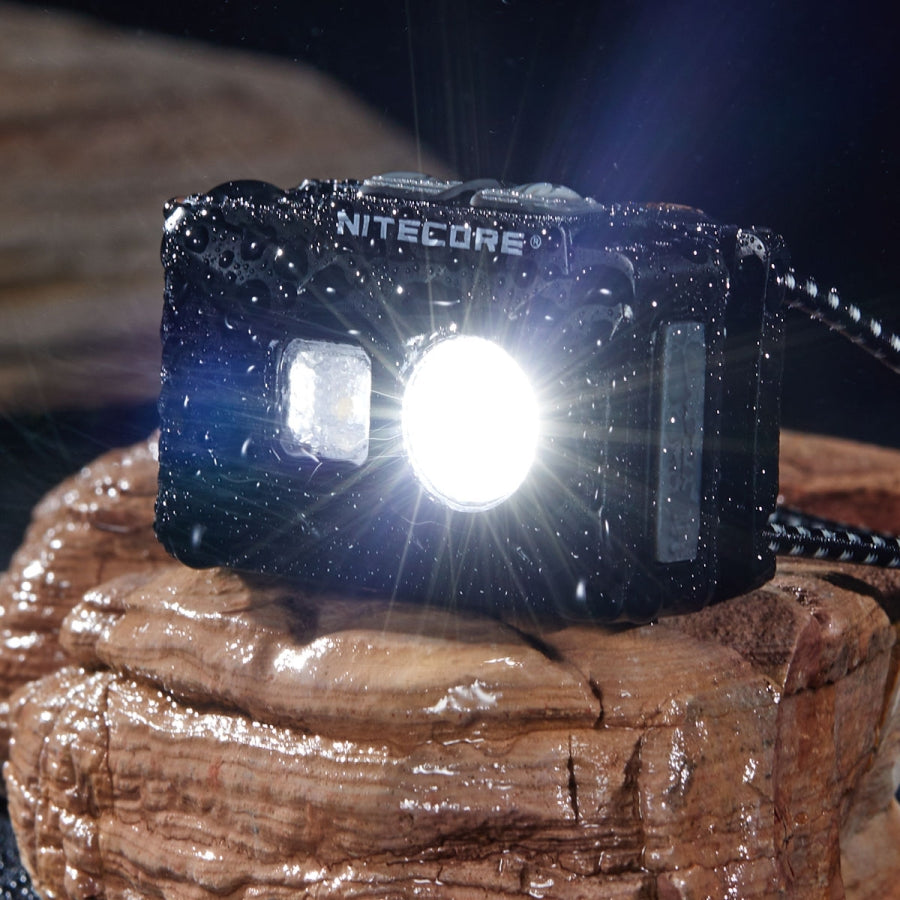 Nitecore flashlight emitting light on a wooden surface