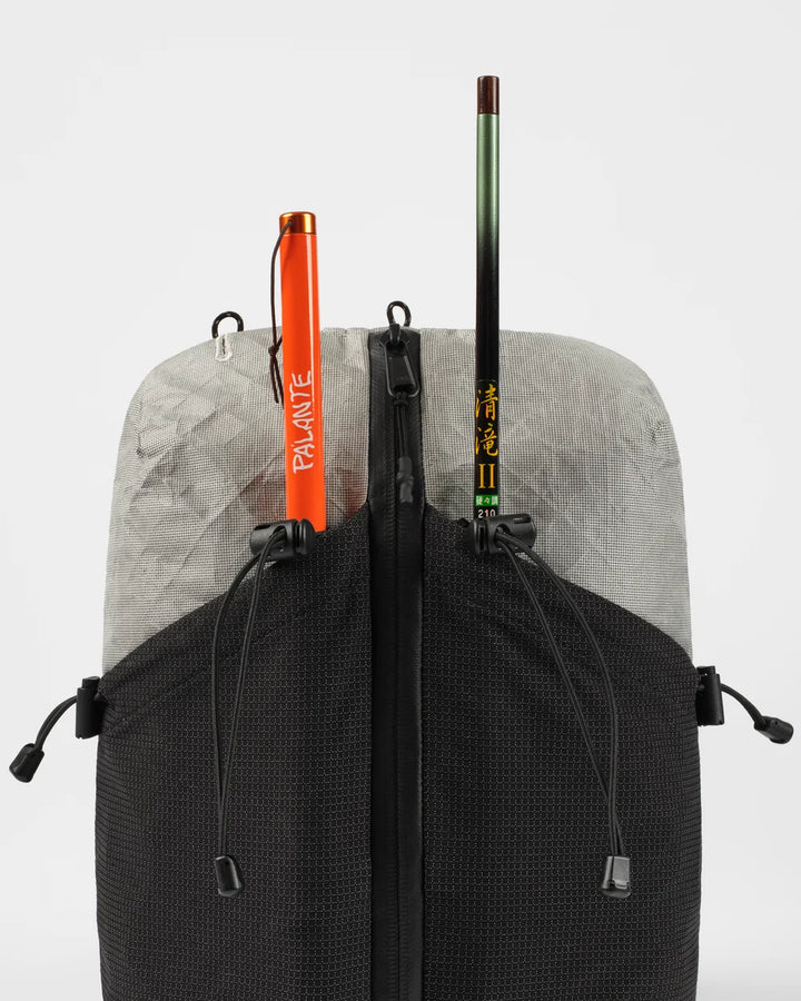 Backpack with two sticks, one orange and one black with yellow text, on a light gray background