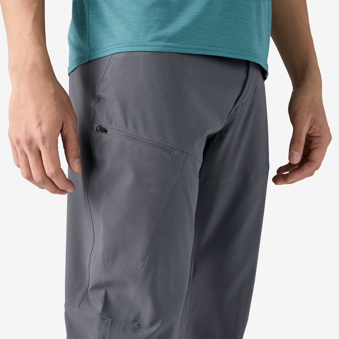 Close up of the right leg of a person wearing grey pants showing a zippered pocket