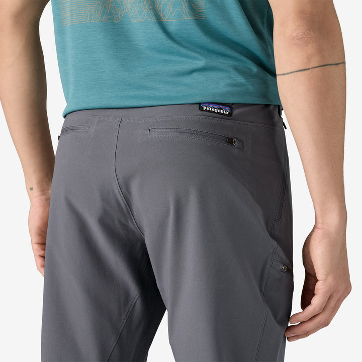 Close up of the butt of a person wearing gray pants showing two zippered pockets on the seat of the pants