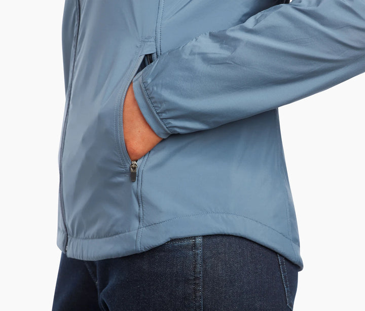 Close up of the lower torso of a woman wearing a light blue jacket with hand in pocket