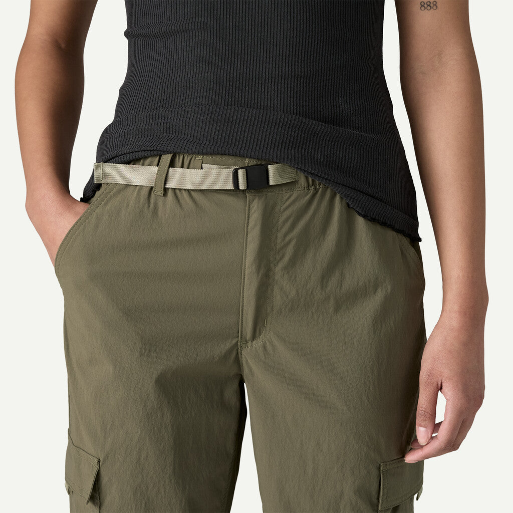 Person wearing olive green cargo pants with a black top on a white background