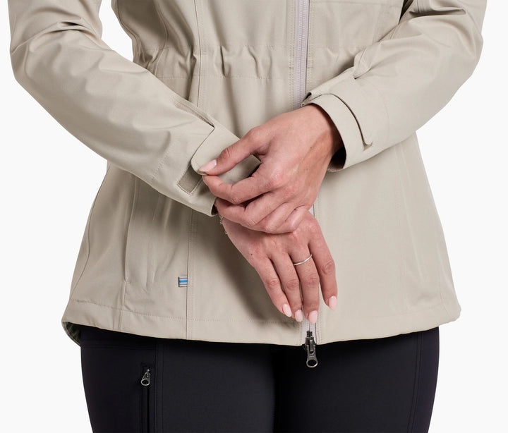 Lower torso of a woman wearing a raincoat, adjusting the velcro on one cuff